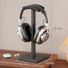 Headphone stand holding a pair of headphones with measurements indicated on a wooden surface.