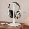 Headphone stand holding a pair of headphones on a wooden surface with measurements indicated.